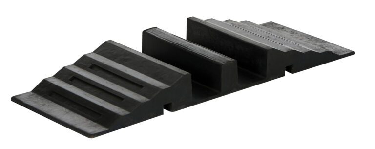 The Vestil Molded Rubber Hose/Cable Crossover 2.4K, a black rubber parking curb with ridges and slots, protects tires and wheel rims from damage with its textured surface, supporting and stabilizing parked vehicles effectively.
