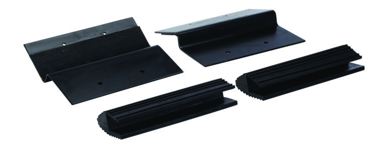 Four black rubber chocks with varying shapes are displayed on a white background. Designed to stabilize vehicles, they are angled and ribbed with mounting holes. These chocks complement the versatility of the Vestil Wooden Ramp Kit 12 X 2 In.