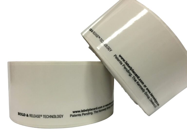 Two large rolls of Vestil Economy Racking Labels 2 In 25 Rolls feature printed text around the core, showcasing website info, trademarks, and Hold & Release technology. The labels are positioned to display both side and top views.