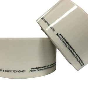 Two rolls of Vestil Industrial Racking Labels (1 In, 25 Pcs) elegantly feature HOLD & RELEASE TECHNOLOGY printed in black at the bottom, along with patent details and a website URL. One roll is playfully tilted atop the other.