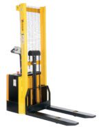 The Vestil Fixed Powered Lift Stacker 62 In Raised has a yellow-black design, long forks, and a safety mesh guard. Its control handle efficiently raises pallets to 62 inches for lifting and transportation in warehouses or industrial settings.