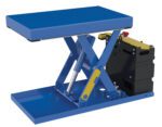 The blue Vestil Scissor Lift Table 20X33 500 Lb 12Dc has a flat platform, sturdy base, and is partially raised. It features a yellow lever and red emergency stop on the black side-mounted control box.
