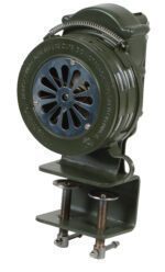 The Vestil Siren - Hand Crank - Metal-Bracket Mount is an olive green, vintage model with a circular grille, coiled spring handle, and adjustable clamps. It features important usage cautions on the front text.