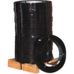 A MH-USA 5/8 x .020 Gauge x 2,360 regular duty steel strapping coil (100 lbs/coil) leans against a stack of black plastic strapping coils on a wooden pallet, showcasing its circular shape. Ideal for bundling and securing items.