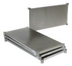 The Vestil Stainless Steel Shelving Kit 48 x 24 inches includes three stacked metal plates with rounded corners, cylindrical supports, and an upright plate in the same style, offering smooth reflective surfaces for a sleek industrial look.