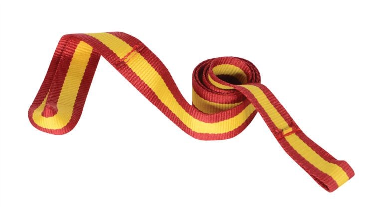 A rolled ribbon with red and yellow stripes resembles the flair of a 3Ft long Vestil Wheel Chock Strap Kit. Partially unrolled, it reveals a wavy pattern against a crisp white background.
