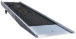 The Vestil Alum Yard Ramp Steel Grating 86In X30 Ft is a metallic ramp with a black grated surface for loading vehicles or equipment onto trailers. It includes wheels on one side for easy maneuverability.