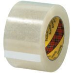 A close-up of a 3 x 55 yds. Clear Scotch® Box Sealing Tape 313 (24/Case) shows its transparent finish, with the inner core displaying a red plaid pattern and Scotch printed on it, while the tape end is gently pulled from the roll.