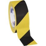 The iconic 2 x 36 yds. Black/Yellow Tape Logic® Striped Vinyl Safety Tape (24/Case) features alternating diagonal stripes partially unrolled, with clear interior labeling for enhanced visibility in safety applications.