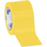 A partially unrolled 3 x 36 yds. Yellow Tape Logic® Solid Vinyl Safety Tape with a glossy finish reveals the inner core branding text, highlighting its reliability. Its available in cases of 16 for ample supply.