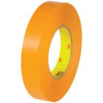 A large roll of 1 x 60 yds. 3M™ 2525 Flatback Tape (36/Case) with an orange adhesive surface and a yellow core featuring the iconic 3M logo, neatly wound to display its smooth, glossy texture against a plain white background.