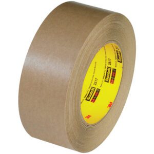 A roll of 3M™ 2517 Flatback Tape, sized at 1 1/2 x 60 yds., features a yellow inner core with the brand label. This brown masking tape, thick and lengthy, is neatly angled to highlight its proportions.