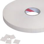 A large roll of adhesive foam tape features a central cutout and includes 3/4 x 3/4 Tape Logic® 1/16 double-sided foam squares, with several small square pieces nearby and perforated sections for easy tearing.