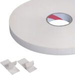A large roll of 1 x 3 Tape Logic® Double Sided Foam Strips (324 Pcs/Roll) reveals the red liner through a cut-out, while two strips in front have one side peeled back to expose the adhesive.
