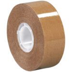 A roll of Tape Logic Heavy-Duty Adhesive Transfer Tape with a white core, shiny surface, and strong brown adhesive side lies on its side. The MH-USA 3/4 x 18 yds. - 2 per case reflects light slightly.