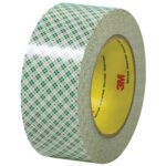 A 2 x 36 yds. roll of 3M™ - 410M Double Sided Masking Tape features a transparent tape with a green and white plaid design and a yellow core with red 3M. It reflects light brilliantly, adding to its glossy allure.