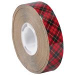 The 1/4 x 18 yds. 3M™ 926 Adhesive Transfer Tape features a red and black plaid design with thin yellow stripes, is partially unwound to show its adhesive layer on a white plastic core, and comes in cases of 72 rolls for crafting needs.
