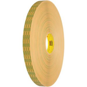The tan 3M™ 465XL Adhesive Transfer Tape roll (1/2 x 60 yds.) features green and black text on its side and a yellow core with red letters. It stands upright against a white background, ready for any task.