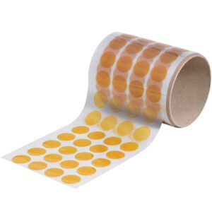 A 3/4 roll of Kapton® Discs (500/Roll), with rows of small orange circular stickers, is unrolled to reveal several dots. Set against a white background, the translucent tape emphasizes their vibrant hue and precision.
