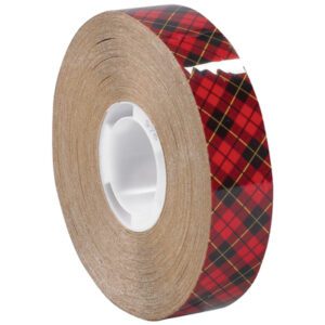 The 3M™ 976 Adhesive Transfer Tape (6 Pack) is a 3/4 x 36 yds. roll with a red plaid pattern accented by black and gold lines. It has a glossy finish, is wound around a white core, and adds flair to any project.