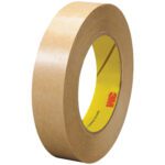 A roll of brown masking tape with a yellow core and red logo stands upright to display its dimensions. Ideal for your needs, its akin to 3M™ 465 Adhesive Transfer Tape Hand Rolls, available in 1 x 60 yds. (6 Pack).