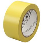 A roll of 2 x 36 yds. Yellow 3M General Purpose Vinyl Tape 764 (24/Case) stands upright on a stark white background, showcasing text on its core.