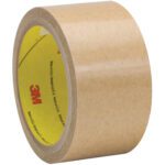 A partially unrolled 3M™ 927 Adhesive Transfer Tape with a tan surface and yellow label featuring the logo; ideal for various tasks. This adhesive is part of a 2 x 60 yds (6 Pack) set, known for its reliable stickiness, available in handy rolls packaged six per case.