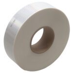 A roll of 2 x 150 White 3M™ 983 Reflective Tape, with a honeycomb pattern and brown cardboard core, is elegantly displayed on its side against a plain white backdrop.