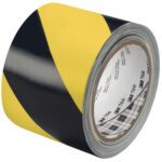 A 2 pack of 3M Safety Stripe Warning Tape 766, measuring 3 x 36 yds., is shown partially unrolled. This black and yellow tape is ideal for marking hazardous areas with its bold diagonal stripes.