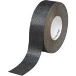 A 2 x 60 Black 3M™ Safety-Walk™ Tape - 510 partially unrolls, displaying its coarse anti-slip surface and visible inner core. This sturdy solution, sold as two rolls per case, ensures maximum safety and convenience.
