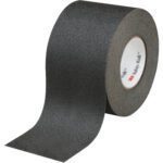 The 4 x 60 Black 3M™ Safety-Walk™ Tape - 610, partially unrolled, showcases its textured surface for grip and safety. The inside branding assures quality and reliability in each roll/case.