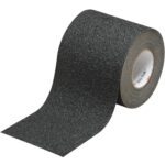 The 6 x 30 Black 3M™ Safety-Walk™ Tape - 710 unfurls, revealing its gritty texture. Designed to enhance grip, it stands out with white edges against a plain white background, ready to boost safety.