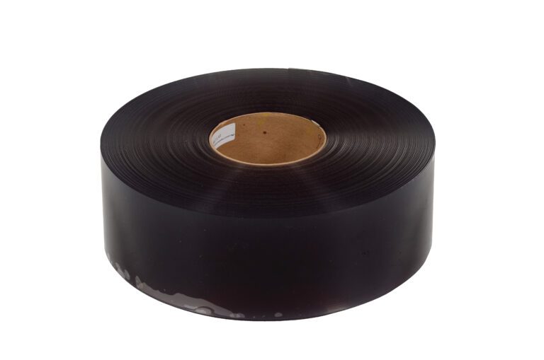 A large roll of black plastic film, similar to the Vestil Roll for Vinyl Strip Door 0.06 Thickness, has a sturdy brown cardboard core, is coiled neatly, and viewed from a slight angle.