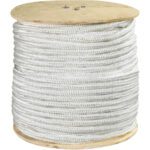 An upright large wooden spool holds MH-USA 3/4 white double braided nylon rope, featuring a dense coil with a 14,500 lb capacity. The neatly wound rope forms a sturdy cylinder, revealing the wooden spool ends at the top and bottom.