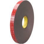 The 3M™ 4919F VHB™ Tape, measuring 1 x 5 yds., sports a large black roll with a red layer and yellow inner core with text. Its designed for reliability, showcasing thickness and durability, making it ideal for various projects.