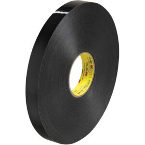 A large roll of 1 x 5 yds. Black 3M™ 4929 VHB™ Tape (1 Roll/Case) with a yellow core shines on a plain white background, emphasizing its glossy, smooth surface.