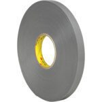 A large roll of 3/4 x 5 yds. Gray 3M™ 4957F VHB™ Tape (1 Roll/Case) with a yellow core stands upright against a white background, appearing thick and sturdy, ideal for heavy-duty tasks.