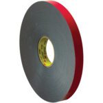 A roll of 1 x 5 yds. black 3M™ 5958FR VHB™ Tape stands upright, displaying its label and demonstrating the brands commitment to quality with its thick, gray design.