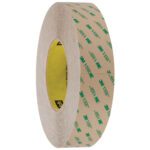 A roll of 1 x 5 yds. Clear 3M™ F9460PC VHB™ Tape is showcased upright, highlighting its circular form and adhesive interior with brown paper backing and green text, underscoring its quality as an essential tool.