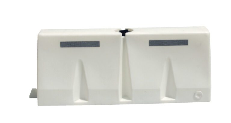 A smooth white, rectangular plastic object with two vertical grooves and small rectangular slots on top, similar to the Vestil Traffic Barriers 5 Ft Wide White Strip. It features a circular indentation on the lower right corner.