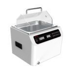 A white sous vide precision cooker with a digital display showing OFF 24.5°C. It has a transparent lid and a handle on top. The front panel features multiple buttons for controls, and there is a drain spout at the bottom front.