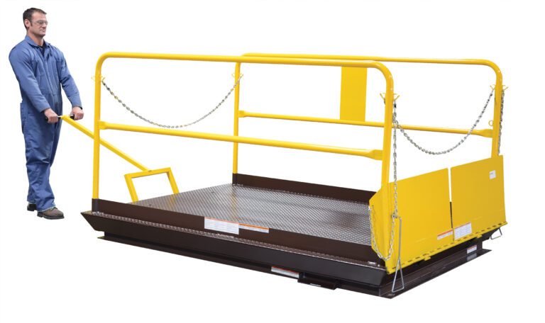A person in blue overalls operates a lift platform with yellow rails and a handle. The platform, featuring protective chains and safety barriers, includes the Vestil Dock Lift Optional Mobile Wheel Kit for better mobility on its diamond-patterned metal surface.