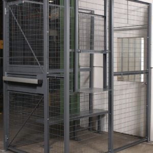 The Vestil Driver/Trucker Access Cage 3 Sided 4X6, set against a white wall, features a sturdy steel frame and lockable door. Ideal for secure storage in warehouses or industrial areas, this metal mesh cage includes practical shelves.