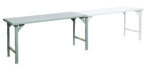 The Little Giant Continuous Width Production Tables boast a long, rectangular shape with gray and white segments supported by robust metal legs, offering a sleek side perspective against a white backdrop.