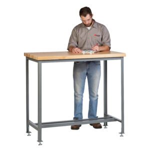 A man in a gray shirt and jeans writes on a clipboard at the Little Giant Counter Height Work Table with Butcher Block Top, supported by sturdy metal legs and adjustable feet, fully engaged in his task.