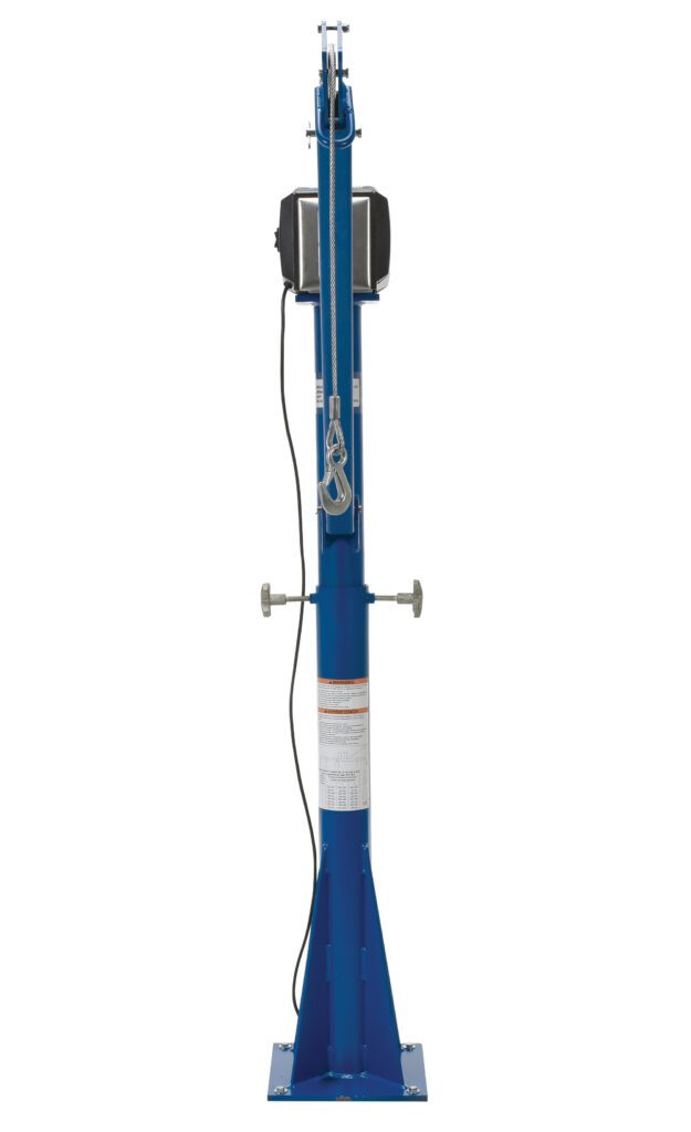 A tall, blue mechanical jack stands upright like the Vestil Ac Power Jib Crane 1.5K 66 In Boom Csa, featuring a visible side crank handle and attached cables. Its wide base ensures stability, and safety warning labels are displayed on the front.
