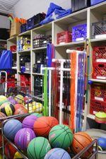 A sports equipment storage room features colorful balls, jump ropes, and more organized on Aurora Quik-Lok Shelving [Adjustable & Heavy Duty Steel – 350 lbs Capacity] Starter Unit, with six openings ensuring neatness.