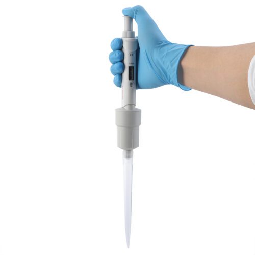 PPT200109 A person wearing a blue glove holds a digital micropipette. The pipette is white with a digital display for precise liquid measurement and showcases a long, clear tip, reflecting the quality seen from top pipette tips suppliers.