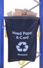 A blue recycling bag labeled Mixed Paper & Card with a recycling symbol is attached to a metal rack. The bag is filled with cardboard. Yellow handles are visible on the sides and bottom.