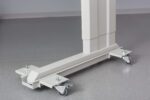 Close-up of a white, adjustable hospital bed base on a grey floor. The base has four wheels with locks, allowing mobility and stability. The design is sleek and functional, suitable for medical environments.